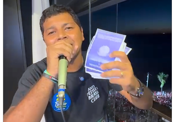 Deputado exibe carteiras de trabalho de papel durante ato do PT em Salvador